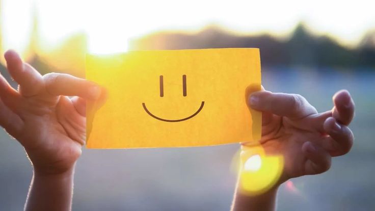 Mãos segurando um cartão com sorriso, simbolizando bem-estar, acolhimento e saúde emocional