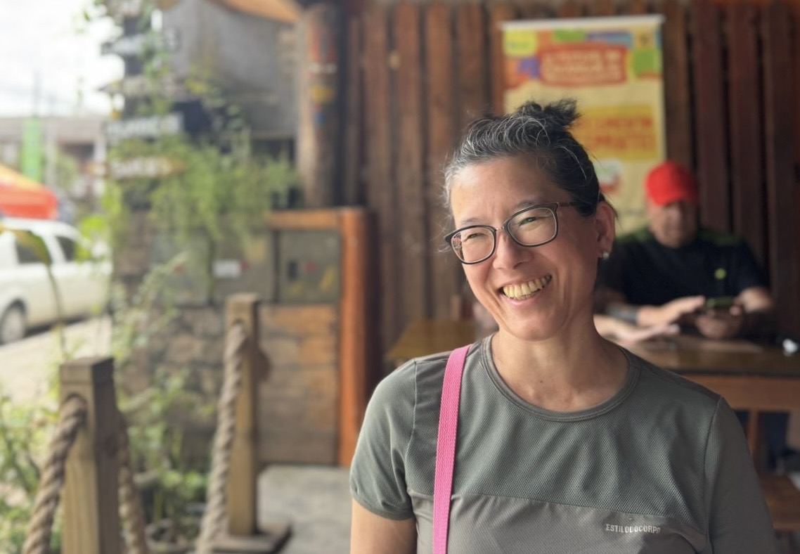 Cristina Massae, terapeuta holística, sorrindo em ambiente natural, transmitindo acolhimento e bem-estar